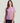 Woman wearing lavender short-sleeve t-shirt with chest pocket and circular logo, paired with black shorts.