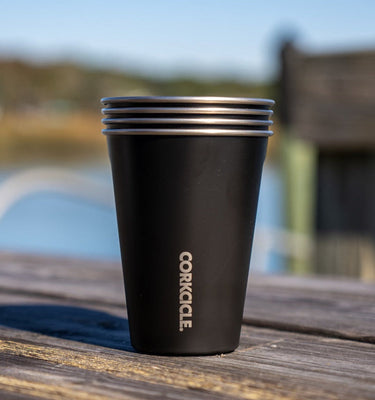 Black Corkcicle cup on a wooden surface with a blurred outdoor background