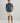 Man wearing navy blue floral short-sleeve button-down shirt with cream shorts and brown sandals.