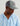 Gray and navy mesh trucker cap with rectangular logo patch worn by person in light blue hoodie.