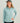 Woman wearing light blue quarter-zip performance hoodie with white logo and text on chest and sleeves, paired with black pant