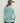 Light blue women's hoodie with textured fabric, shown from back view with hood down.