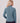 Woman wearing a blue-gray fleece half-zip jacket with long sleeves, shown from the back.