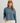 Woman wearing HUK Women's Leeward Boxy Fleece Hoodie in Stormy Blu Heather