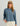 Woman wearing HUK Women's Leeward Boxy Fleece Hoodie in Stormy Blu Heather
