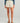 Cream-colored swim short with tie waist and subtle leaf pattern, worn with blue long-sleeve top.
