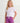 Girl wearing white t-shirt with coral logo and purple volley shorts with white drawstring.