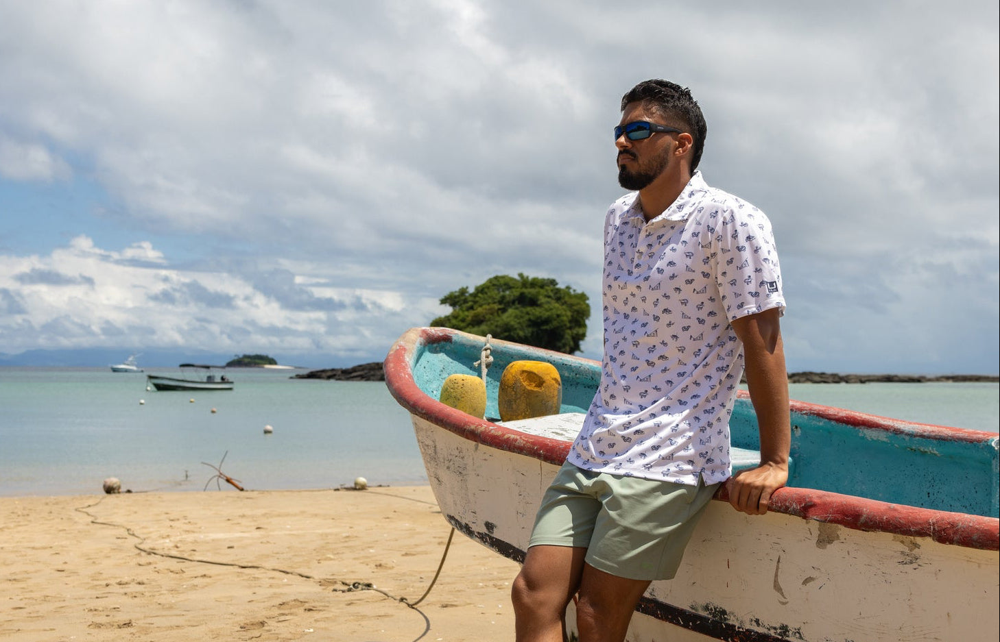 Man sitting on a boat on a beach with a clear sky and water in the background