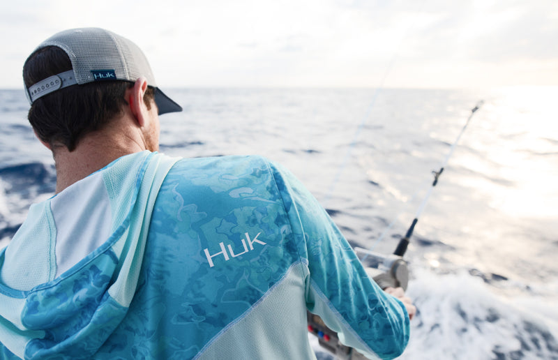 Angler reeling in offshore under backlit morning sun