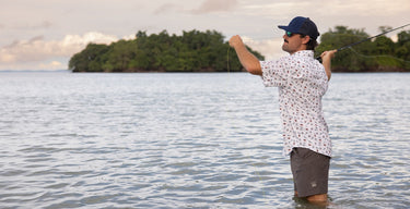 Man fishing in a body of water with trees in the background
