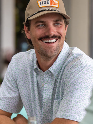 Man wearing a cap with 'HUK' logo, smiling outdoors.